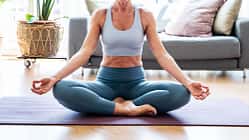Ältere, sportliche Dame praktiziert Yoga auf einer Gymnastikmatte