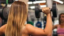 Nahaufnahme einer Frau von hinten mit starken Schultern beim Schulterdrücken.