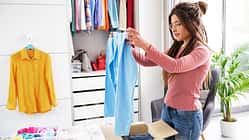 Young,Woman,Folding,Her,Clothes,And,Packing,Them,In,A