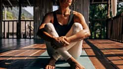 Frau sitzt auf einer Yoga-Matte mit angewinkelten Knien