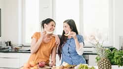 Two happy women in kitchen preparing fruit