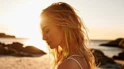 Eine Frau mit blonden Haaren am Strand bei Sonnenuntergang
