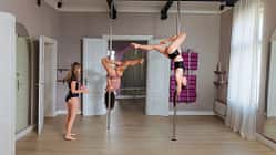 Poledance-Instruktorin coacht zwei junge Frauen in einem Tanzstudio