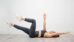 Woman performing dead bug exercise lowering opposite arm and leg for functional core training