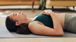Frau liegt entspannt mit geschlossenen Augen auf einer Yogamatte