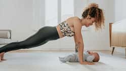 Eine Frau beugt sich lächelnd in Liegestützposition über ihr Baby. Eine Frau beugt sich lächelnd in Liegestützposition über ihr Baby.