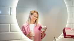 Frau mit einer Packung OMNi-BiOTiC® WOMAN und einem Glas in der Hand liest, was auf der Packung steht