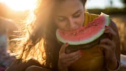 Eine Frau beißt im Sonnenlicht in eine Wassermelone