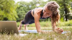 Frau macht im Park ein Workout mit einem Youtube-Video über ihren Laptop 