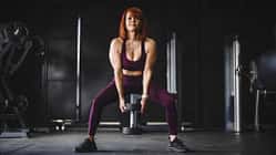 Eine trainierte Frau macht Kniebeugen mit einer Kettlebell