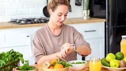 Eine Frau schaut auf ihren Fitnesstracker, während sie gesundes Essen verzehrt