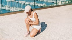 Eine Frau in Sportkleidung fasst sich an ihr Knie beim Outdoor-Training