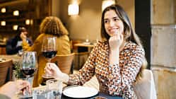 Eine Frau sitzt im Restaurant und trinkt ein Glas Rotwein