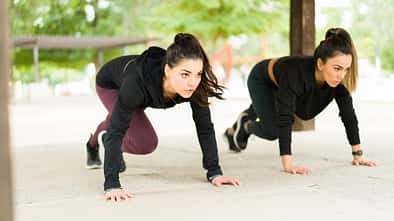 Zwei Frauen in dunkler Kleidung führen Mountain Climbers (Bergsteiger) aus.