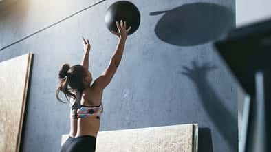Frau wirft einen Medizinball an die Wand