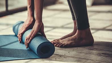 Frau rollt eine Yogamatte ein