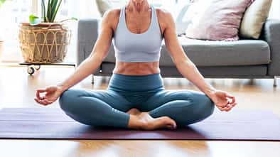 Ältere, sportliche Dame praktiziert Yoga auf einer Gymnastikmatte