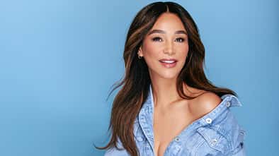 Verona Pooth lächelt in die Kamera vor blauem Hintergrund
