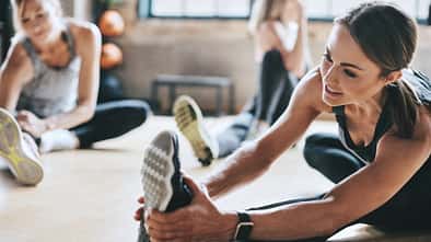 Drei Frauen dehnen sich in einem Fitnessstudio.