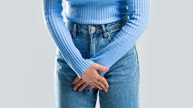 Frau schämt sich und hält ihre Hände vorm Intimbereich