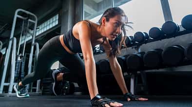 Frau macht eine Stützübung am Boden im Gym und schwitzt