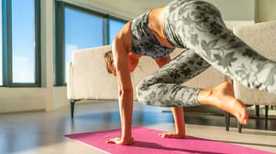 Frau macht eine Plank-Variante auf dem Boden.