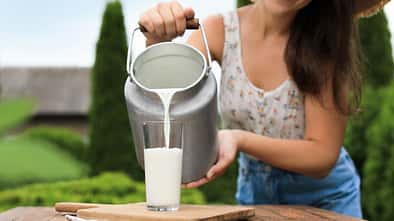 junge Frau kippt frische Milch in ein Glas