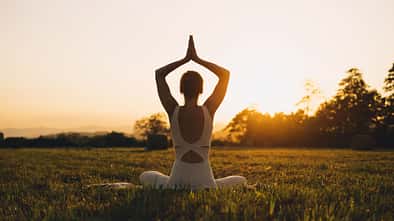 Junge Frau übt in der Natur Yoga-Übungen aus