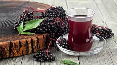Glas mit Holundersaft und Holunderbeeren