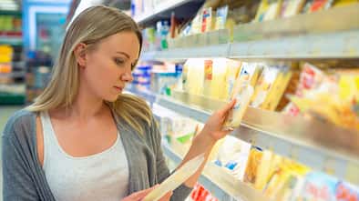 Woman,Choosing,Cheese,In,Grocery,Store.