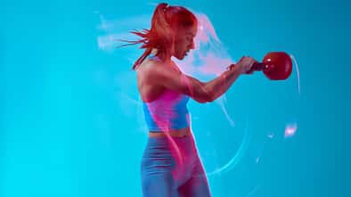 Eine weibliche Bodybuilderin, die Kettlebell im Studio hebt. 