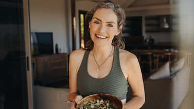 Fröhliche Frau, die einen Gemüsesalat aus einer Schüssel isst