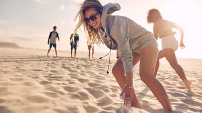 Young woman running race with friends at the beach