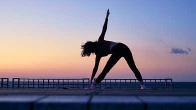 Eine Frau macht eine Yoga-Pose vor dem Sonnenaufgang