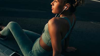 Junge Frau, die während des Trainings Musik über ihre Kopfhörer hört