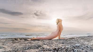 Frau macht Cobra-Position am Strand