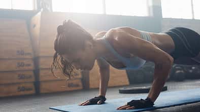 Shot,Of,Young,Woman,Doing,Push-ups,At,The,Gym.,Muscular