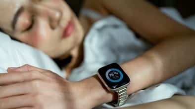 Woman sleeping peacefully in bed, wearing a smart watch to track her sleep