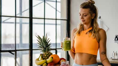 Trainierte Frau mit Smoothie und Obst