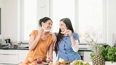 Two happy women in kitchen preparing fruit