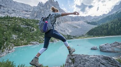 Frau springt über Steine in Berglandschaft