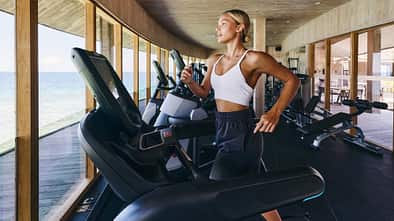 Frau trainiert mit Meerblick auf einem Crosstrainer
