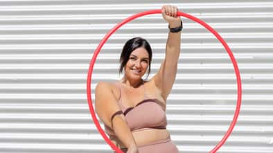 Eine kurvige Frau in Sportkleidung mit einem Hula-Hoop-Reifen