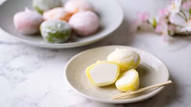 verschiedenes Mochi-Eis auf Tellern angerichtet, mit gelben Mochis im Vordergrund