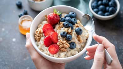 Eine Frau hält eine gesunde Schale mit Porridge Eine Frau hält eine gesunde Schale mit Porridge