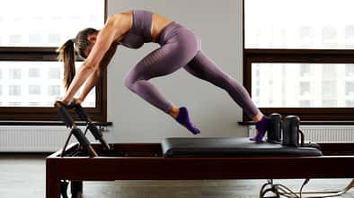 Eine Frau macht Pilates-Übungen an einer Reformer-Pilates-Maschine