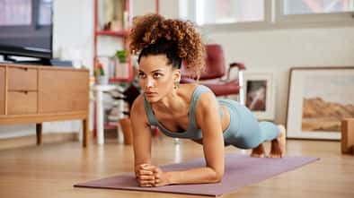 Eine Frau macht Planks auf einer Yogamatte Eine Frau macht Planks auf einer Yogamatte