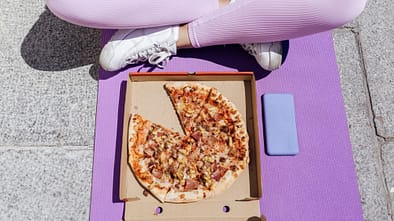 Eine Frau sitzt im Schneidersitz und isst Pizza Eine Frau sitzt im Schneidersitz und isst Pizza