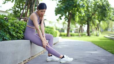 Woman Massaging Sore Leg After Exercise