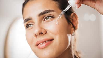 Young woman applying serum on face